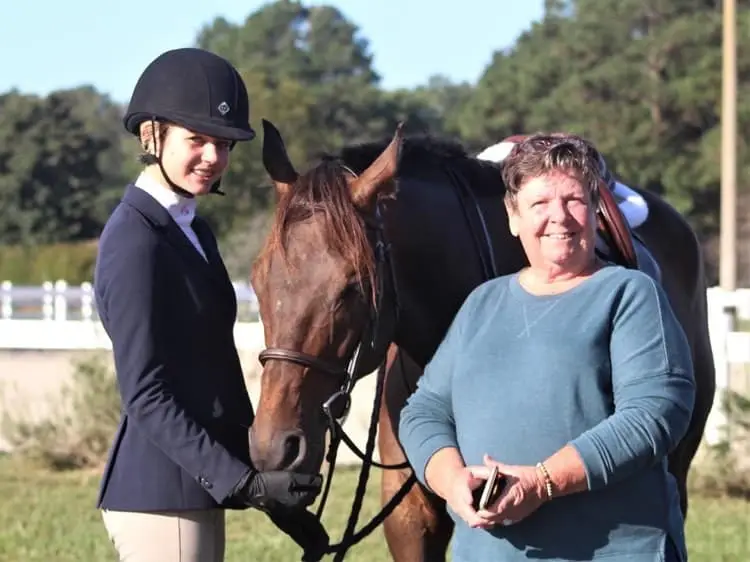 Photo of Betty Mills with her protege, Maggie, and their competition horse, Legacy Danseur.