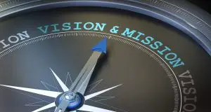 Photo of compass needle pointing to vision & mission.