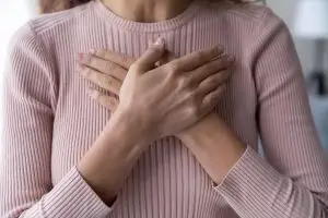 Photo of grateful woman holding hands over her heart.