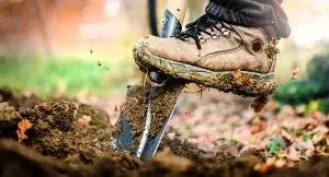 Photo of a man digging a hole by using a shovel.