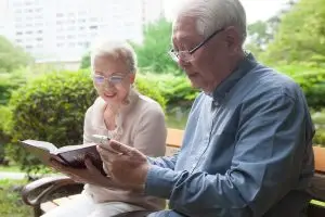 Photo of older couple reading the Bible outdoors.