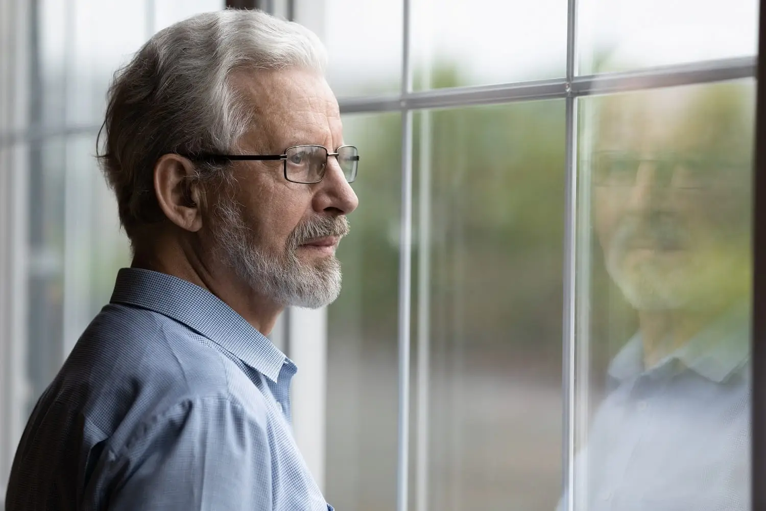 Photo of a sad man looking out a window with regret.