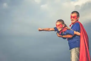 Photo of superman father helping his young daughter to fly confidently.
