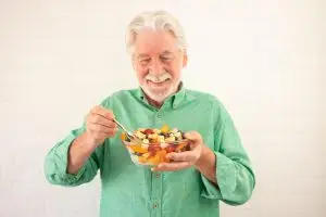 Photo of an older man eating a bowl of fruit.