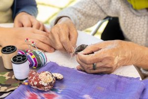 Photo of daughter helping elderly mother with crafts.