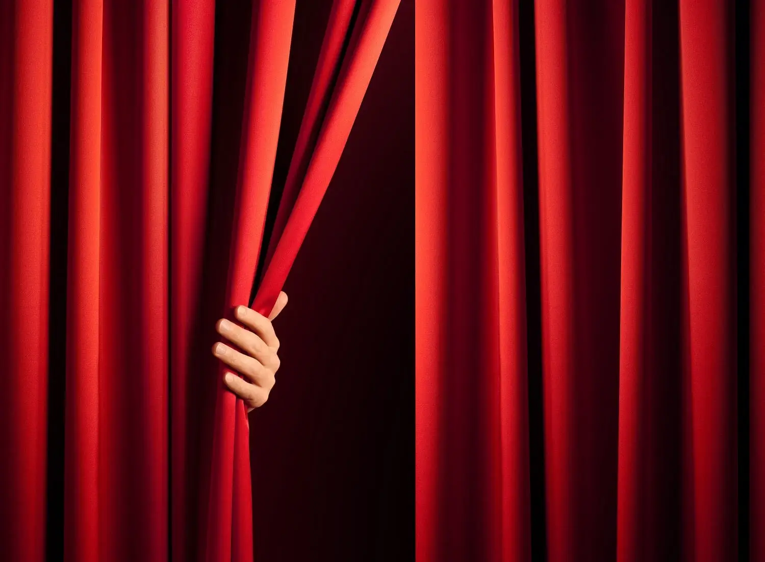 Photo of someone pulling a theater curtain open to start the second act.