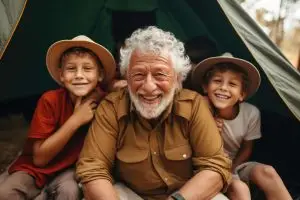 Photo of an older man with two boys near a tent.