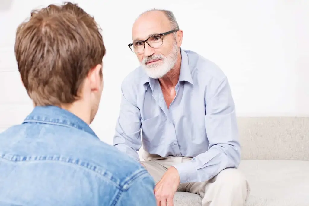 Photo of an older man sharing a story with a younger man.
