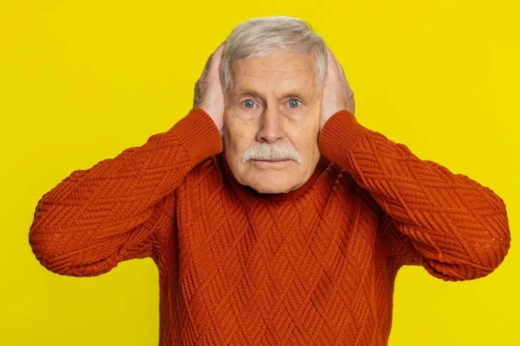 Photo of older man covering his ears.