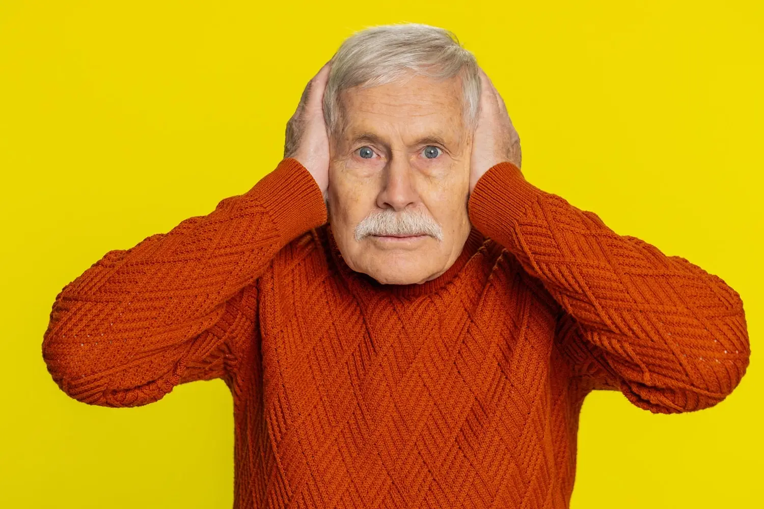 Photo of older man covering his ears.