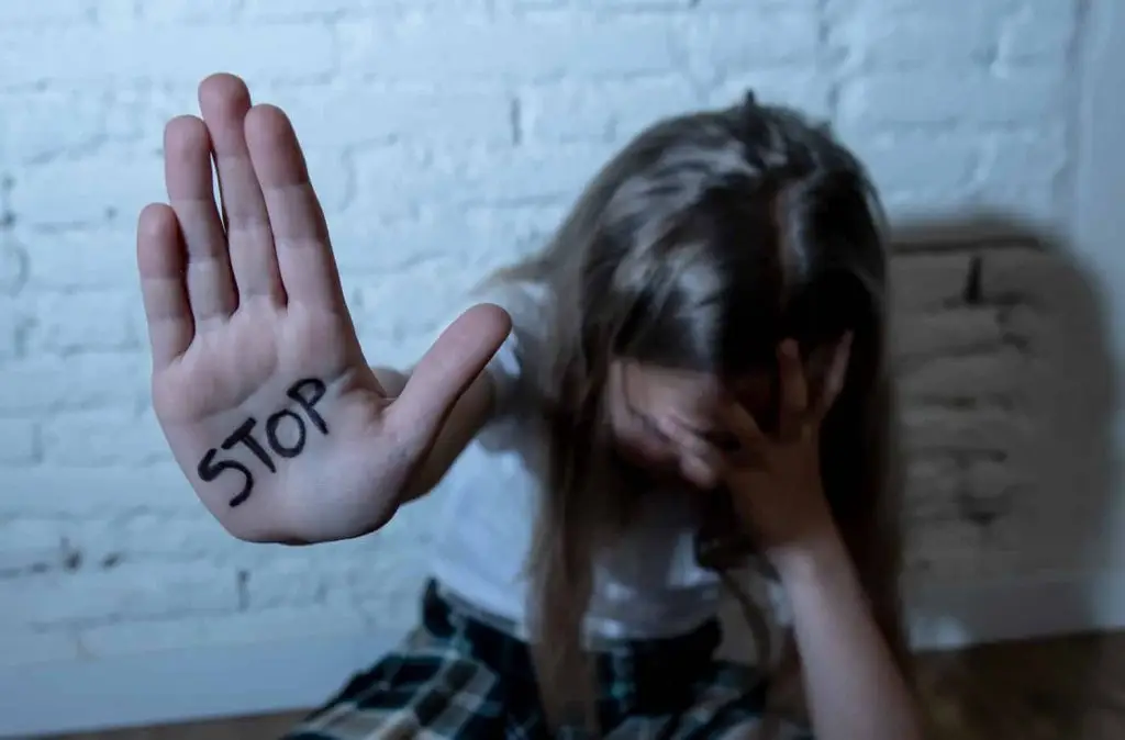 Photo of a girl pleading to stop the trauma being inflicted upon her.