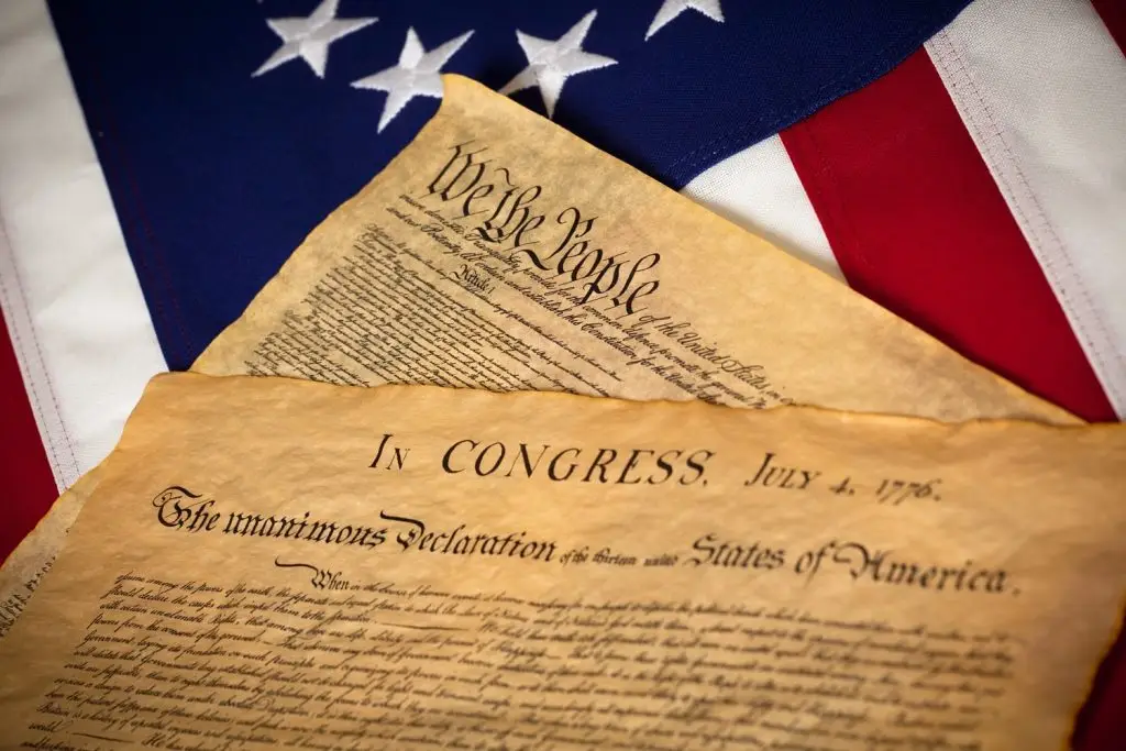 Photo of the U.S. Constitution and Declaration of Independence with the American flag in the background.
