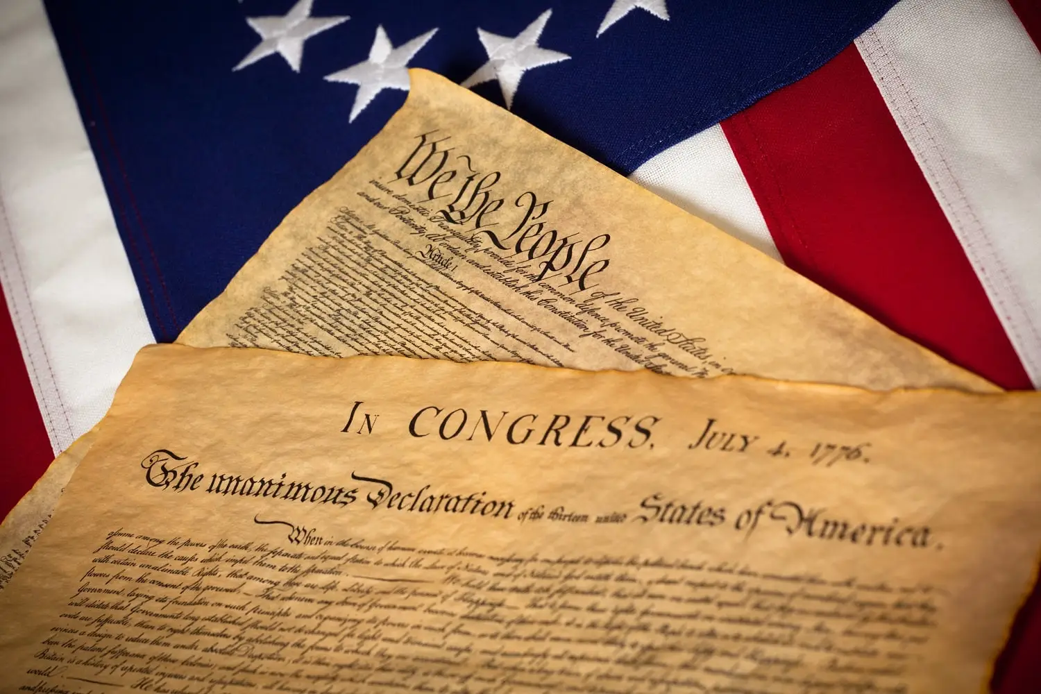 Photo of the U.S. Constitution and Declaration of Independence with the American flag in the background.