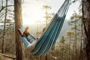 Photo of a man relaxing on a hammock in the wilderness.