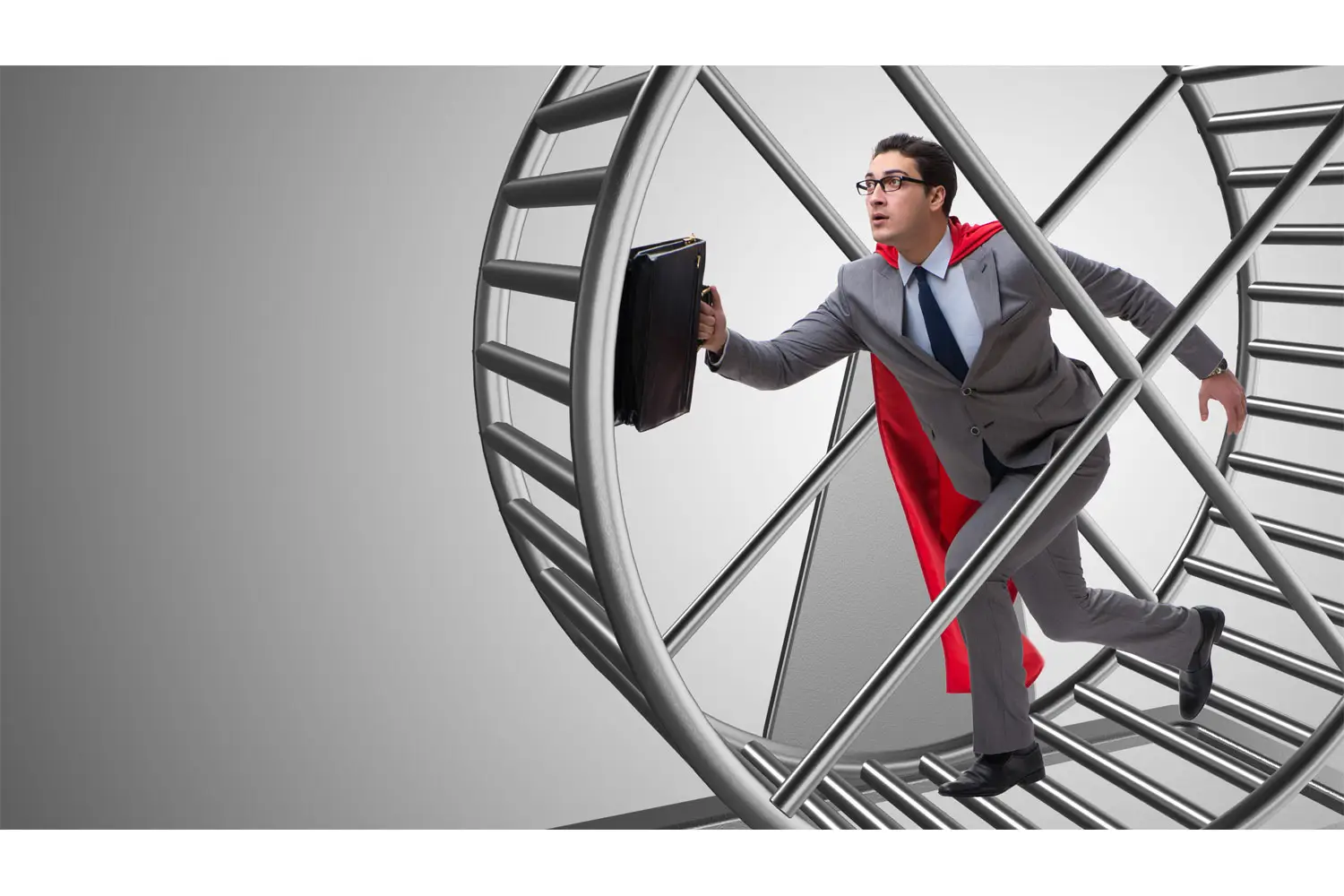 Photo of businessman wearing a Superman cape and running on a hamster wheel.
